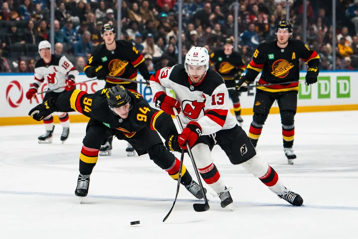 Vancouver Canucks forward Linus Karlsson (94) stick checks New Jersey Devils forward Nico Hischier (13) in the third period at Rogers Arena.