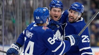 Maple Leafs players David Kampf, Conor Timmins and Noah Gregor celebrating a goal during a game.