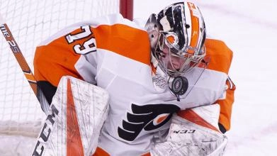Philadelphia Flyers goaltender Carter Hart making a save with his mask in an away game in the NHL.