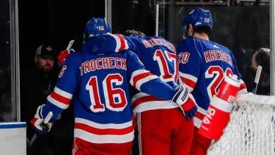 Vincent Trocheck and Chris Kreider of the New York Rangers carrying teammate Blake Wheeler off the ice after an injury.