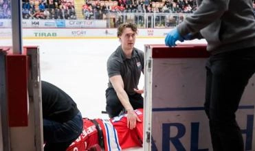 Trainer for Timra of the Swedish Hockey League attending to Sebastian Hartmann who was injured by a skate blade.