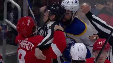 Detroit Red Wings' Ben Chiarot hitting the linesman Ben O'Quinn by accident in a scrum involving Jordan Greenway in a game.