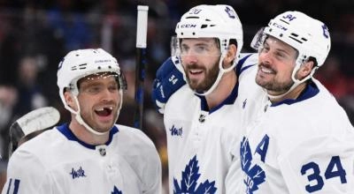 Max Domi, Auston Matthews, and Joel Edmundson of the Toronto Maple Leafs celebrating a goal.