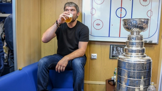 Alex Ovechkin of the Washington Capitals drinks beer while sitting near the Stanley Cup