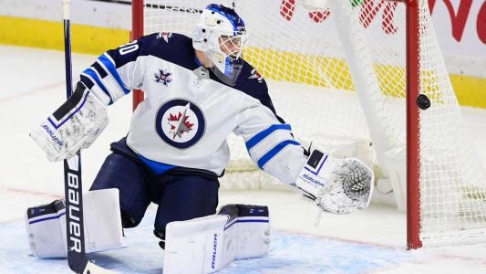 Former Winnipeg Jets goalie Laurent Brossoit making a save during a road game in the NHL.