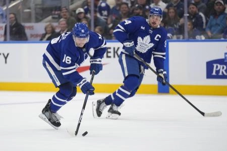 Mar 19, 2025; Toronto, Ontario, CAN; Toronto Maple Leafs forward Mitch Marner (16) gets control of the puck as forward Auston Matthews (34) trails the play against the Colorado Avalanche during the third period at Scotiabank Arena. Mandatory Credit: John E. Sokolowski-Imagn Images
