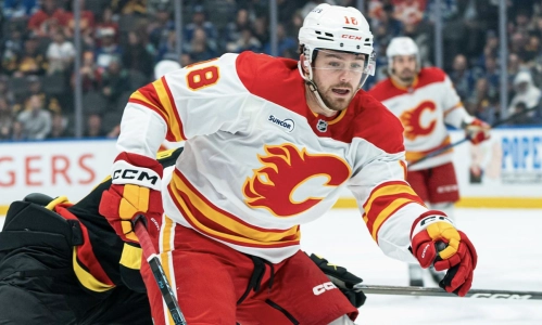 John Beecher (18) des Flames de Calgary r&eacute;siste au tacle d'Elias Pettersson (40) des Canucks de Vancouver alors qu'il se dirige vers le filet lors de la troisi&egrave;me p&eacute;riode du match de la LNH &agrave; la Rogers Arena, le 23 novembre 2025 &agrave; Vancouver, au Canada.