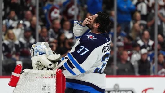 Winnipeg Jets' Connor Hellebuyck with his mask off as he cleans his face