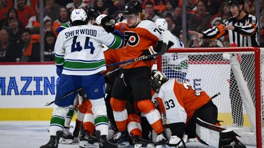 Philadelphia Flyers' Owen Tippett gets shoved by Vancouver Canucks' Kiefer Sherwood