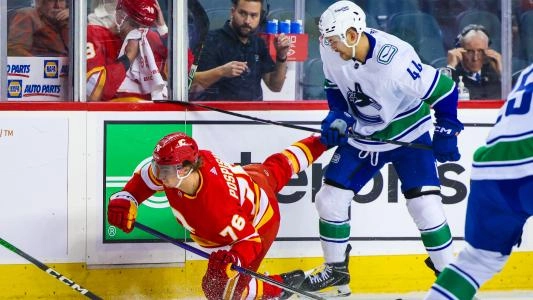 Vancouver Canucks' Jett Woo trips a Calgary Flames player