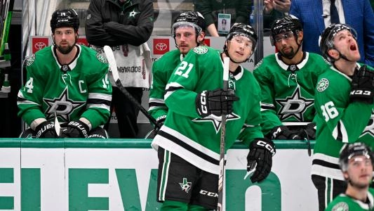 Dallas Stars' Matt Dumba sits on the bench next to his teammates