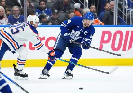 Dec 13, 2025; Toronto, Ontario, CAN; Toronto Maple Leafs center Auston Matthews (34) battles for the puck with Edmonton Oilers defenseman Darnell Nurse (25) during the third period at Scotiabank Arena.