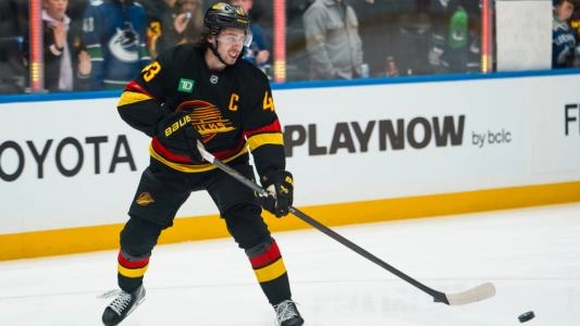 Vancouver Canucks' Quinn Hughes plays the puck