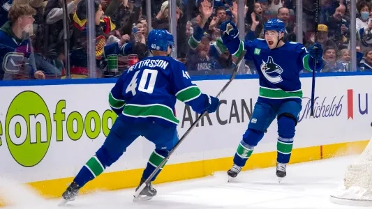 Vancouver Canucks' Elias Pettersson skates to Nils Hoglander to celebrate