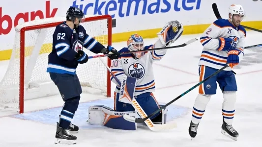 Winnipeg Jets and Edmonton Oilers players battle in front of the net