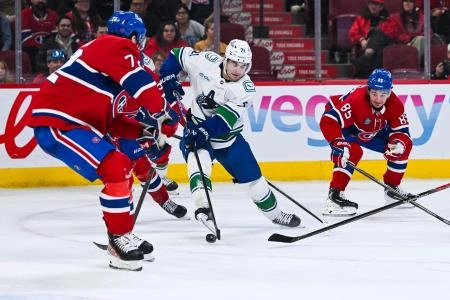 Jan 12, 2026; Montreal, Quebec, CAN; Vancouver Canucks left wing Nils Hoglander (21) plays the puck against Montreal Canadiens defenseman Arber Xhekaj (72) during the third period at Bell Centre. Mandatory Credit: David Kirouac-Imagn Images
