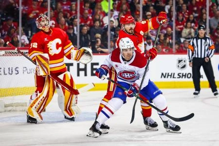 8 mars 2025; Calgary, Alberta, Canada; Alex Newhook (15), centre des Canadiens de Montr&eacute;al, et MacKenzie Weegar (52), d&eacute;fenseur des Flames de Calgary, se disputent la position devant le gardien des Flames de Calgary, Dustin Wolf (32), durant la premi&egrave;re p&eacute;riode au Scotiabank Saddledome.