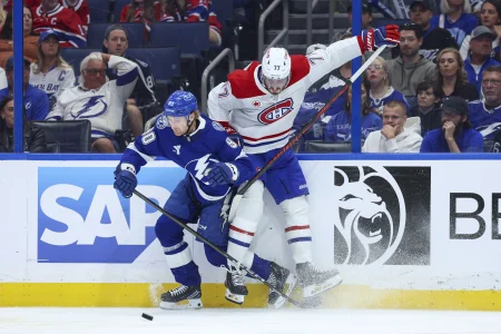 Apr 21, 2026; Tampa, Florida, USA; Tampa Bay Lightning defenseman J.J. Moser (90) and Montreal Canadiens center Kirby Dach (77) battle for the puck in the third period during game two of the first round of the 2026 Stanley Cup Playoffs at Benchmark International Arena.
