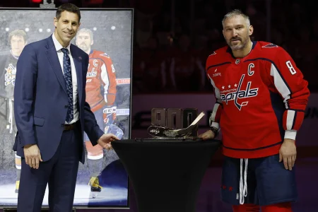 Nov 26, 2025; Washington, District of Columbia, USA; Washington Capitals left wing Alex Ovechkin (8) is presented a gift trophy from Capitals players and front office, represented by Capitals senior vice president and general manager Chris Patrick (L) during a ceremony honoring his 900th NHL career goal and 1,500th game with the Capitals prior to their game against the Winnipeg Jets at Capital One Arena.
