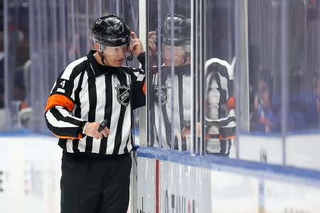 Mar 24, 2025; Elmont, New York, USA; NHL referee Wes McCauley (4) puts on a headset for a video review of a disallowed Islanders goal during the third period between the New York Islanders and the Columbus Blue Jackets at UBS Arena.