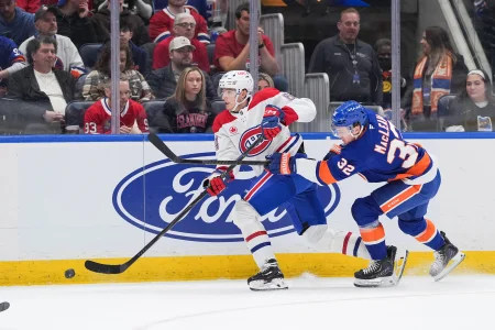 12 avril 2026 ; Elmont, New York, États-Unis ; Le défenseur des Canadiens de Montréal David Reinbacher (64) fait une passe tandis que le centre des Islanders de New York Kyle MacLean (32) se lance à sa poursuite au cours de la deuxième période à l'UBS Arena. Crédit obligatoire : Alexander Wohl-Imagn Images