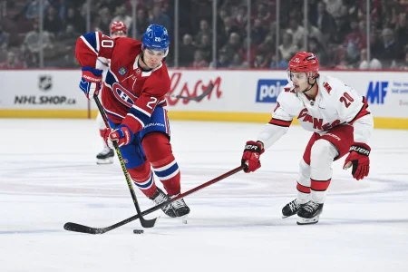 Feb 25, 2025; Montreal, Quebec, CAN; Montreal Canadiens left wing Juraj Slafkovsky (20) plays the puck against Carolina Hurricanes center Sebastian Aho (20) in the first period at Bell Centre.