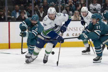 Apr 11, 2026; San Jose, California, USA; Vancouver Canucks center Linus Karlsson (94) controls the puck during the third period against San Jose Sharks defenseman Nick Leddy (4) and San Jose Sharks center Macklin Celebrini (71) at SAP Center at San Jose.