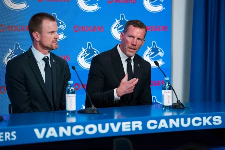 May 14, 2026; Vancouver, BC, Canada; Daniel Sedin listens to Ryan Johnson speak during a press conference where the Vancouver Canucks name new senior management staff. Henrik Sedin and his twin brother Daniel Sedin have been appointed as co-presidents of hockey operations and Ryan Johnson is now the new general manager of the club at Rogers Arena.