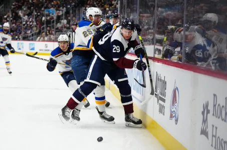 Nov 11, 2023; Denver, Colorado, USA; St. Louis Blues center Jordan Kyrou (25) hits Colorado Avalanche center Nathan MacKinnon (29) in the first period at Ball Arena.
