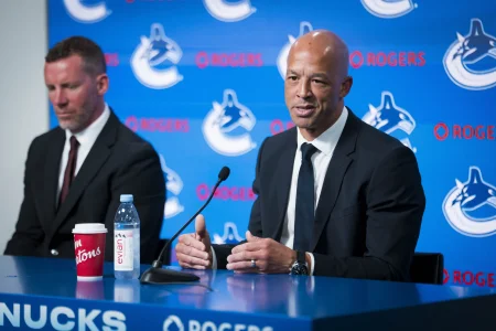 Jun 4, 2026; Vancouver, BC, CANADA; General manager Ryan Johnson listens to Manny Malhotra speak during press conference where the Vancouver Canucks introduce Malhotra as their new head coach during a press conference at Rogers Arena.