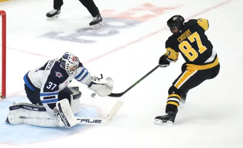 Mar 21, 2026; Pittsburgh, Pennsylvania, USA; Winnipeg Jets goaltender Connor Hellebuyck (37) makes a save against Pittsburgh Penguins center Sidney Crosby (87) in overtime at PPG Paints Arena.