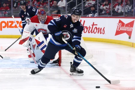 4 février 2026; Winnipeg (Manitoba, Canada); Cole Perfetti (91), centre des Jets de Winnipeg, contrôle la rondelle face au gardien des Canadiens de Montréal, Samuel Montembeault (35), en deuxième période au Centre Canada Life.