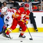 Jan 23, 2026; Calgary, Alberta, CAN; Calgary Flames center Nazem Kadri (91) and Washington Capitals center Aliaksei Protas (21) battle for the puck during the second period at Scotiabank Saddledome.