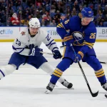 Dec 21, 2023; Buffalo, New York, USA; Buffalo Sabres defenseman Rasmus Dahlin (26) controls the puck as Toronto Maple Leafs left wing Matthew Knies (23) defends during the third period at KeyBank Center. Mandatory Credit: Timothy T. Ludwig-Imagn Images