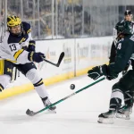 Michigan center TJ Hughes makes a pass against Michigan State defenseman Nash Nienhuis during the third period at Yost Ice Arena in Ann Arbor on Friday, Feb. 9, 2024.