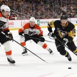 Mar 7, 2026; Pittsburgh, Pennsylvania, USA; Pittsburgh Penguins center Tommy Novak (18) moves the puck against Philadelphia Flyers defenseman Travis Sanheim (6) and right wing Matvei Michkov (39) in overtime at PPG Paints Arena. Mandatory Credit: Charles LeClaire-Imagn Images