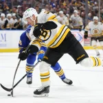 Mar 25, 2026; Buffalo, New York, USA; Buffalo Sabres center Sam Carrick (10) tries to block a shot by Boston Bruins center Morgan Geekie (39) during the first period at KeyBank Center. Mandatory Credit: Timothy T. Ludwig-Imagn Images