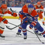 Apr 22, 2026; Edmonton, Alberta, CAN; Anaheim Ducks forward Cutter Gauthier (61) tries to knock the puck away from Edmonton Oilers forward Connor McDavid (97) during the first period in game two of the first round of the 2026 Stanley Cup Playoffs at Rogers Place.