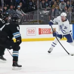 Mar 10, 2025; Salt Lake City, Utah, USA; Toronto Maple Leafs center Auston Matthews (34) takes a shot as Utah Hockey Club center Nick Schmaltz (8) and center Clayton Keller (9) defend during overtime at Delta Center. Mandatory Credit: Rob Gray-Imagn Images