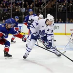 Dec 15, 2022; New York, New York, USA; Toronto Maple Leafs center Auston Matthews (34) controls the puck against New York Rangers defenseman Adam Fox (23) and goaltender Igor Shesterkin (31) during the first period at Madison Square Garden.