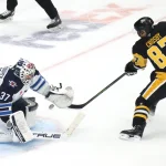 Mar 21, 2026; Pittsburgh, Pennsylvania, USA; Winnipeg Jets goaltender Connor Hellebuyck (37) makes a save against Pittsburgh Penguins center Sidney Crosby (87) in overtime at PPG Paints Arena.
