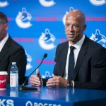 Jun 4, 2026; Vancouver, BC, CANADA; General manager Ryan Johnson listens to Manny Malhotra speak during press conference where the Vancouver Canucks introduce Malhotra as their new head coach during a press conference at Rogers Arena. Mandatory Credit: Bob Frid-Imagn Images