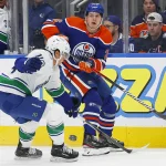 Dec 23, 2022; Edmonton, Alberta, CAN; Edmonton Oilers forward Mattias Janmark (26) makes a pass in front of Vancouver Canucks defensemen Ethan Bear (74) during the first period at Rogers Place. Mandatory Credit: Perry Nelson-Imagn Images