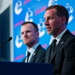 May 14, 2026; Vancouver, BC, Canada; Daniel Sedin listens to Ryan Johnson speak during a press conference where the Vancouver Canucks name new senior management staff. Henrik Sedin and his twin brother Daniel Sedin have been appointed as co-presidents of hockey operations and Ryan Johnson is now the new general manager of the club at Rogers Arena.