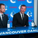 May 14, 2026; Vancouver, BC, Canada; Daniel Sedin listens to Ryan Johnson speak during a press conference where the Vancouver Canucks name new senior management staff. Henrik Sedin and his twin brother Daniel Sedin have been appointed as co-presidents of hockey operations and Ryan Johnson is now the new general manager of the club at Rogers Arena.