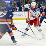 Jan 28, 2026; Elmont, New York, USA; New York Rangers left wing Alexis Lafrenière (13) attempts a shot defended by New York Islanders defenseman Tony DeAngelo (77) during the first period at UBS Arena.