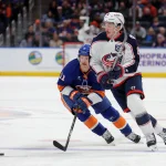 Mar 22, 2026; Elmont, New York, USA; Columbus Blue Jackets defenseman Zach Werenski (8) plays the puck against New York Islanders left wing Emil Heineman (51) during the first period at UBS Arena.