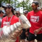 Jun 20, 2026; Raleigh, North Carolina, USA; Carolina Hurricanes left wing William Carrier (28) and defenseman K'andre Miller (19) walk out with the Stanley Cup trophy during the Stanley Cup championship parade and rally at Raleigh