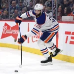 Jan 8, 2026; Winnipeg, Manitoba, CAN; Edmonton Oilers defenseman Darnell Nurse (25) shoots the puck up the ice during a game against the Winnipeg Jets in the second period at Canada Life Centre. Mandatory Credit: James Carey Lauder-Imagn Images