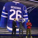 Jun 26, 2026; Buffalo, New York, USA; Gavin McKenna puts on a sweater beside NHL commissioner Gary Bettman and singer Justin Bieber after being selected with the first pick in the first round of the 2026 NHL Draft by the Toronto Maple Leafs at KeyBank Center.
